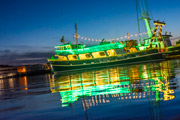 Photo of the Coral Sea research vessel on the water with green and gold lights