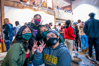 a group of students with masks on smiling for the camera in the new student activities center