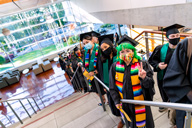 students dressed in colorful graduation attire standing on the stairs waiting to for graduation
