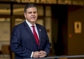 Joseph Castro eighth CSU Chancellor standing in front of a building