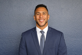 Michael Lynch wearing a suit standing in front of a grey blue wall