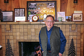Cal Mukumoto standing in front of a fire place